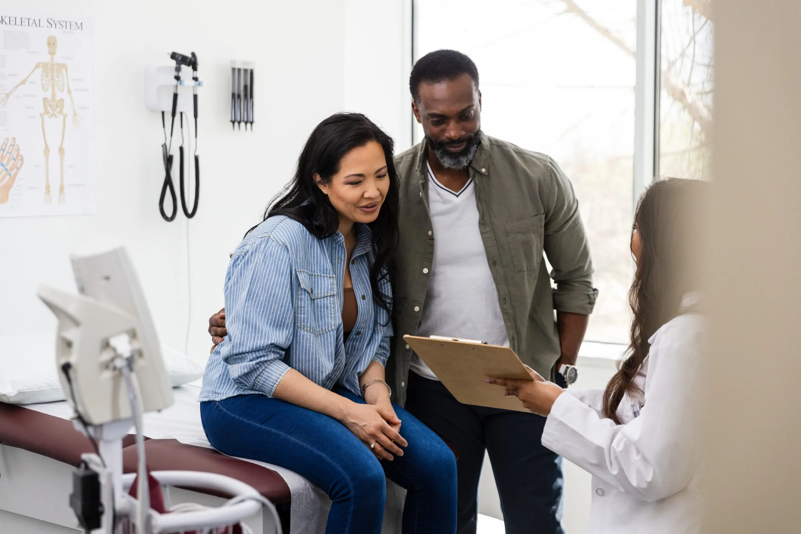 Unrecognizable female doctor talks with the couple in the clinic